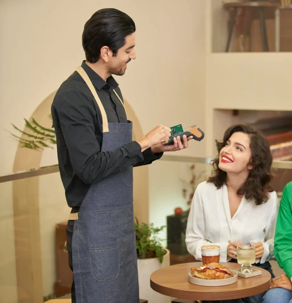 Male merchant processing payment from female customer in restaurant.